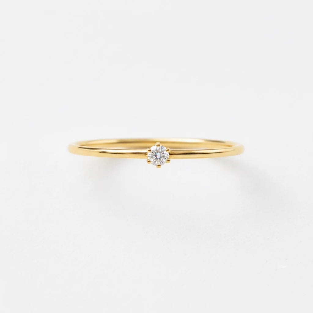Gold ring with a diamond on a light gray background