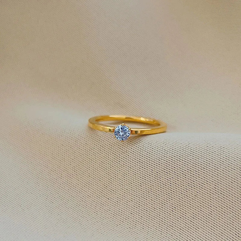 Gold ring with a blue gemstone on a beige fabric background